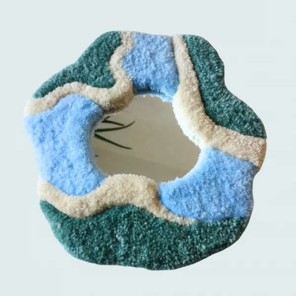 Photo d'Acis, miroir tufté en gros plan. Laine acrylique dans les tons blanc, vert foret, bleu et orange.