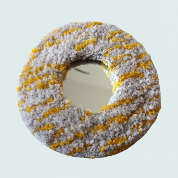 Photo de Clay donut, miroir tufté. Laine acrylique dans les tons blanc et jaune.
